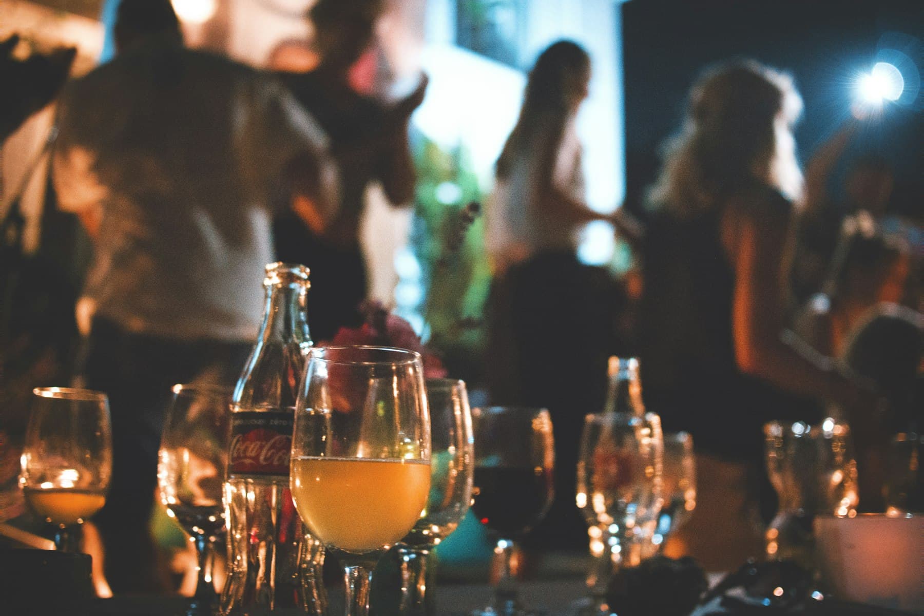 Guests mingling at an evening function with drinks in the foreground — event coverage.