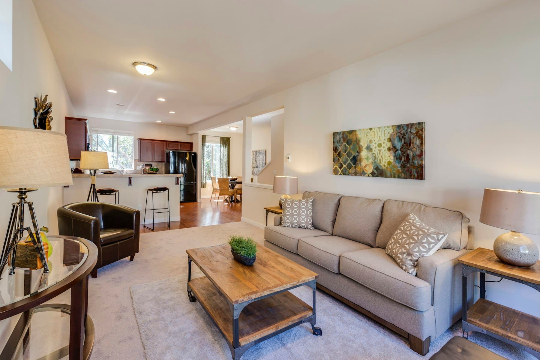 Furnished living room with sofa, coffee table and open-plan kitchen in a property listing photo